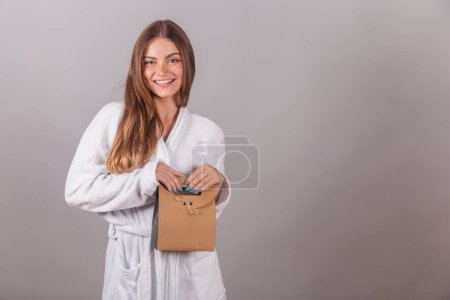 Photo for Brazilian blonde woman showing wonderful hair. dressed in a robe. holding cardboard bag with cosmetics. - Royalty Free Image