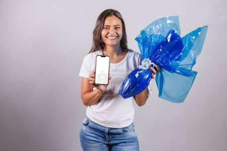 Photo for Brazilian woman, Easter, holding smartphone and Easter egg. - Royalty Free Image