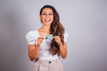 Photo for Brazilian woman, brown hair, holding driver's license, Brazilian document. - Royalty Free Image