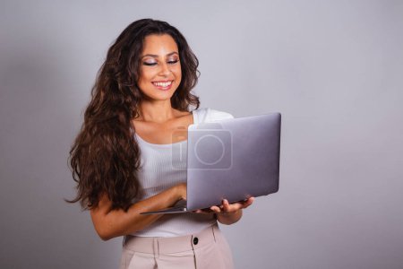 Photo for Brazilian woman holding notebook. browsing the web, websites, computerization. Internet. - Royalty Free Image