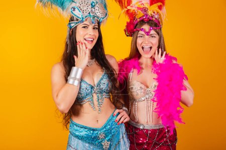 Téléchargez les photos : Deux amies brésiliennes avec des vêtements de reine de l'école de samba, carnaval. Couronne de plumes. wow, incroyable. - en image libre de droit