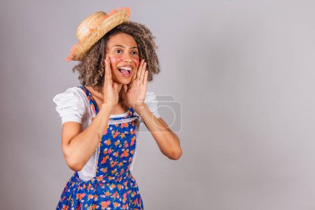 Foto de Joven brasileña negra, con ropa de campo, vestida para Festa Junina. Festival de San Juan. promoción gritando, publicidad. - Imagen libre de derechos