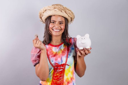 Foto de Mujer brasileña vistiendo ropa de campo, fiesta So Joo, fiesta Junina. tenencia de alcancía y moneda. - Imagen libre de derechos