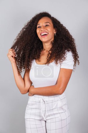 Photo for Vertical photo, beautiful black Brazilian woman, dressed in white, casual clothes, smiling. - Royalty Free Image