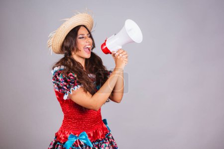 Foto de Mujer brasileña, con ropa de fiesta de junio. Festival de San Juan. con megáfono gritando y anunciando descuentos y promoción. - Imagen libre de derechos
