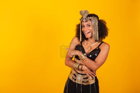 Photo for Beautiful black Brazilian woman, in Cleopatra carnival clothes, presenting something to the left. - Royalty Free Image