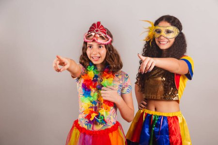 Téléchargez les photos : Des amies brésiliennes, vêtues de vêtements de carnaval. pointant quelque chose au loin. - en image libre de droit