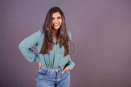 Foto de Foto horizontal. Hermosa mujer brasileña, con ropa casual, Jeans y camisa verde. manos en el bolsillo sonriendo. - Imagen libre de derechos