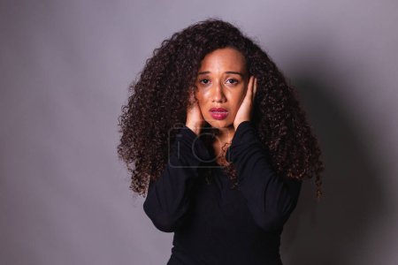 Téléchargez les photos : Femme afro en faveur de la sensibilisation aux fémicides. Violence domestique. couvrant les oreilles. - en image libre de droit