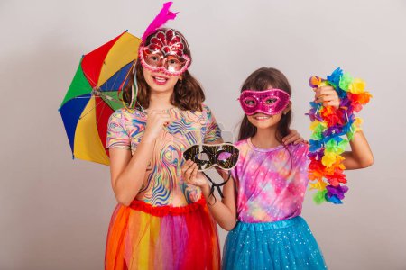 Photo for Two Brazilian children, girls, dressed in carnival outfit, holding carnival accessories. - Royalty Free Image