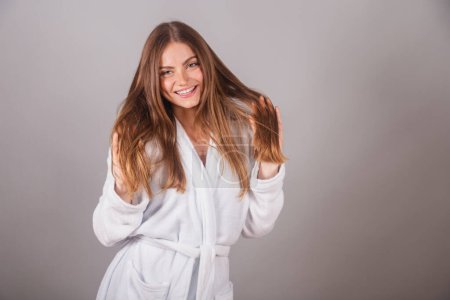 Photo for Brazilian blonde woman showing wonderful hair. Wearing a bathrobe. Messing with hair, hair with movement. - Royalty Free Image