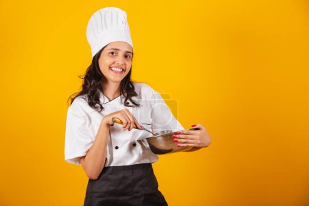Photo for Brazilian woman, head chef, cook, holding spoon and bowl. mixing. - Royalty Free Image