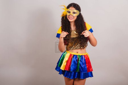 Foto de Jovencita adolescente, brasileña, con ropa frevo, carnaval. máscara, apuntando a la cámara, eligiéndote. - Imagen libre de derechos
