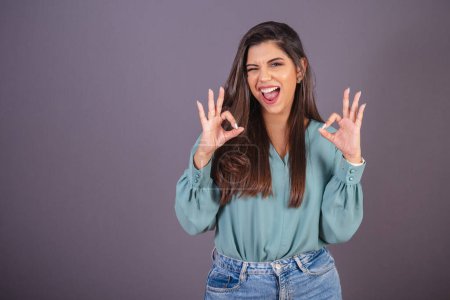 Photo for Horizontal photo. Beautiful Brazilian woman, with casual clothes, Jeans and green shirt. ok sign, all right. - Royalty Free Image