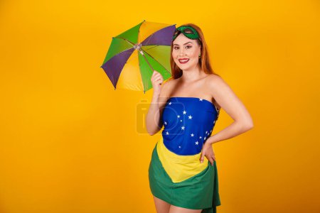 Foto de Hermosa pelirroja brasileña con ropa de carnaval hecha con bandera de Brasil, y sombrilla colorida. - Imagen libre de derechos