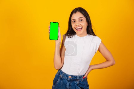 Téléchargez les photos : Belle femme brésilienne tenant smartphone, montrant écran chromé vert. - en image libre de droit