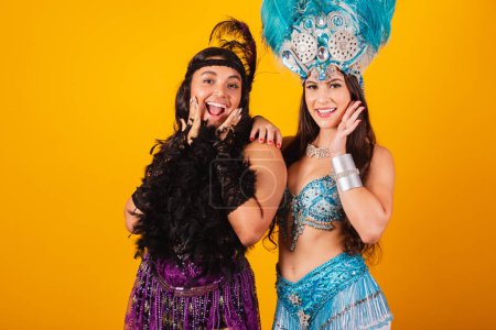 Téléchargez les photos : Deux amies brésiliennes avec des vêtements de reine de l'école de samba, carnaval. Couronne de plumes. posant pour la photo. - en image libre de droit