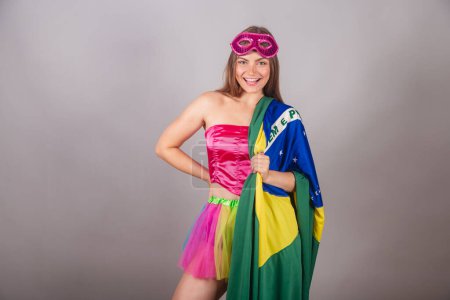 Téléchargez les photos : Femme blonde brésilienne vêtue de vêtements de carnaval rose. portant un mascara, avec drapeau brésilien. - en image libre de droit