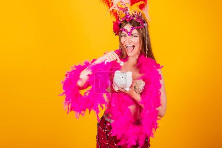 Foto de Hermosa mujer brasileña rubia con ropa de reina de la escuela de samba, carnaval. Corona de plumas. tenencia de alcancía y moneda. - Imagen libre de derechos