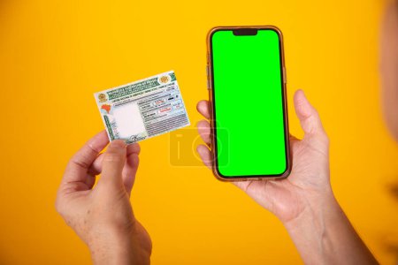 Photo for Hand holding Brazilian car and vehicle driving license, CNH, smartphone with green screen - Royalty Free Image