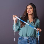 Horizontal photo. Beautiful Brazilian woman, with casual clothes, Jeans and green shirt. nutritionist holding measuring tape.
