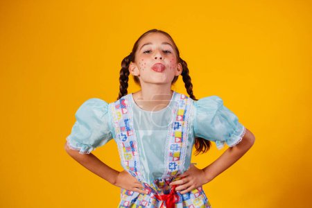 Téléchargez les photos : Enfant en vêtements typiques de la célèbre fête brésilienne appelée "Festa Junina" pour célébrer So Joo. Belle fille sur fond jaune
. - en image libre de droit