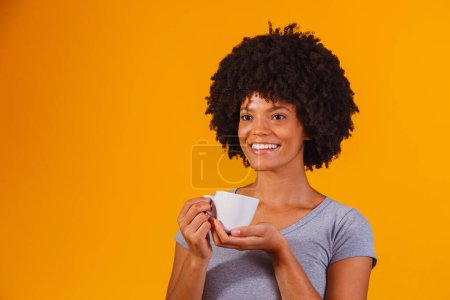 Photo for Afro woman taking tea on yellow background - Royalty Free Image