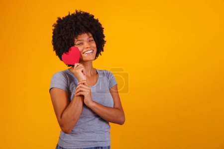 Photo for Portrait Of Girl Isolated Holding a Paper Heart Over yellow Background - Royalty Free Image