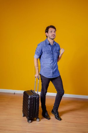 Foto de Hombre con maleta y pasaporte sobre fondo amarillo. concepto de viaje - Imagen libre de derechos