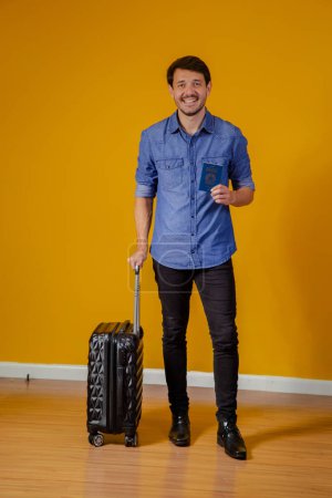 Téléchargez les photos : Homme avec valise et passeport sur fond jaune. concept de voyage - en image libre de droit