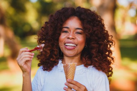Foto de Mujer afro feliz comiendo helado en el parque. - Imagen libre de derechos