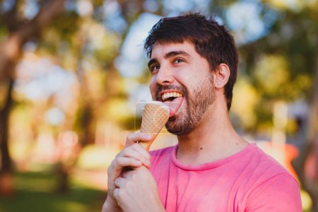 Foto de Joven hombre guapo comiendo helado en el parque - Imagen libre de derechos