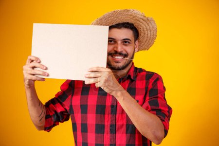 Photo for Brazilian man wearing typical clothes for the Festa Junina holding sign with space for text - Royalty Free Image