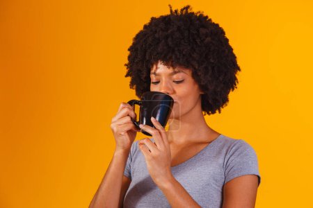 Foto de Afro mujer tomando té sobre fondo amarillo - Imagen libre de derechos