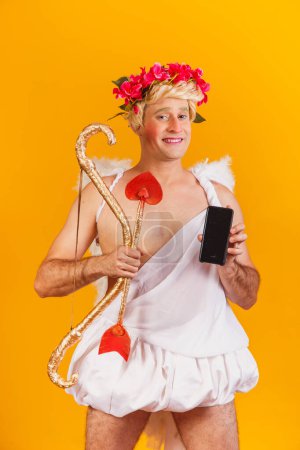 Photo for Cupid holding cell phone. Valentine's Day promotion - Royalty Free Image