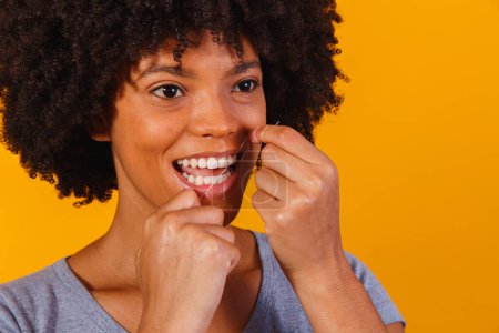 Foto de Una mujer afro usando hilo dental. concepto de salud oral - Imagen libre de derechos