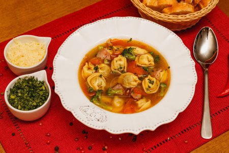 Téléchargez les photos : Délicieuse soupe aux nouilles aux légumes, soupe aux nouilles aux légumes, sur fond de bois, fond de tissu rouge, avec pain grillé, persil et parmesan, plats d'hiver brésiliens, cuisine gastronomique - en image libre de droit