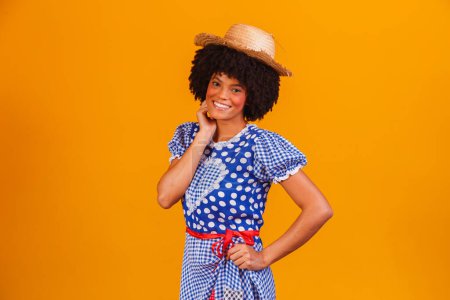 Photo for Brazilian afro woman wearing typical clothes for the Festa Junina in yellow background - Royalty Free Image