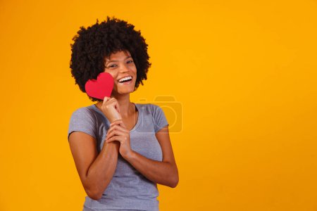 Photo for Portrait Of Girl Isolated Holding a Paper Heart Over yellow Background - Royalty Free Image