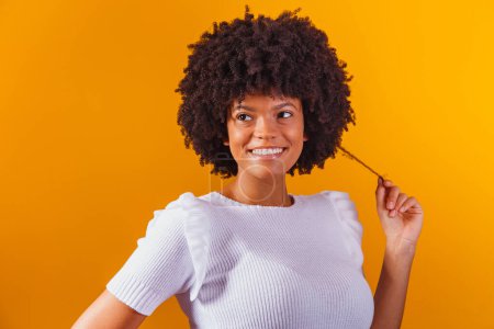Téléchargez les photos : Portrait de beauté de femme afro-américaine avec coiffure afro et maquillage glamour. Une Brésilienne. Mixte. Cheveux bouclés. Coiffure. Fond jaune - en image libre de droit