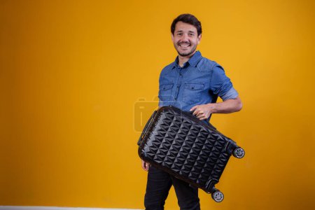 Téléchargez les photos : Homme heureux tenant valise souriant regardant la caméra - en image libre de droit