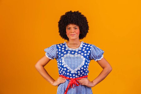 Photo for Brazilian afro woman wearing typical clothes for the Festa Junina in yellow background - Royalty Free Image