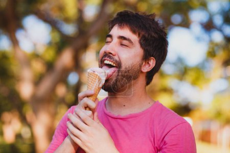 Photo for Young handsome man eating ice cream in the park - Royalty Free Image