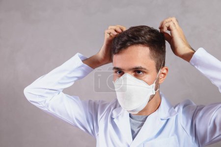 Foto de Joven doctor poniéndose máscara protectora - Imagen libre de derechos