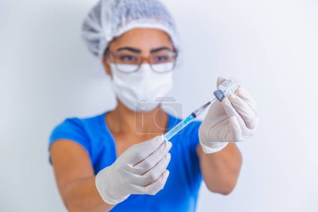 Téléchargez les photos : Vaccin COVID-19 entre les mains d'un chercheur, une femme médecin tient une seringue et un flacon avec un vaccin pour guérir le coronavirus. Concept de traitement du virus corona, injection, injection et essai clinique pendant la pandémie. - en image libre de droit