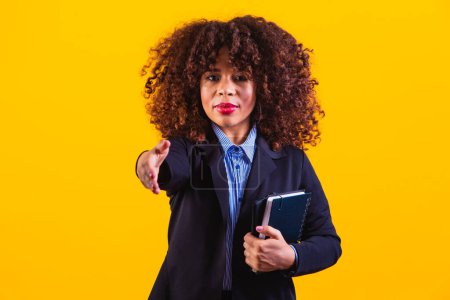 Téléchargez les photos : Femme d'affaires afro-américaine d'âge moyen sur un fond jaune isolé tendre la main à la caméra dans un geste de salutation. - en image libre de droit