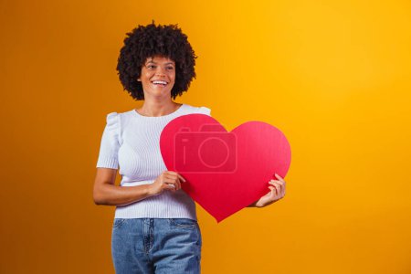 Photo for Photo portrait of smiling afro woman holding big red heart card - Royalty Free Image