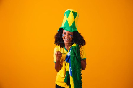 Foto de Abanico brasileño. Abanico brasileño celebrando partido de fútbol o fútbol sobre fondo amarillo. Colores de Brasil. - Imagen libre de derechos