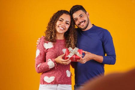 Téléchargez les photos : Portrait d'un beau couple sur fond jaune avec un cadeau - en image libre de droit