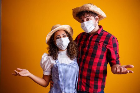 Photo for Couple wearing typical clothes for the Festa Junina (Junina Party) and protection mask to prevent COVID-19. - Royalty Free Image